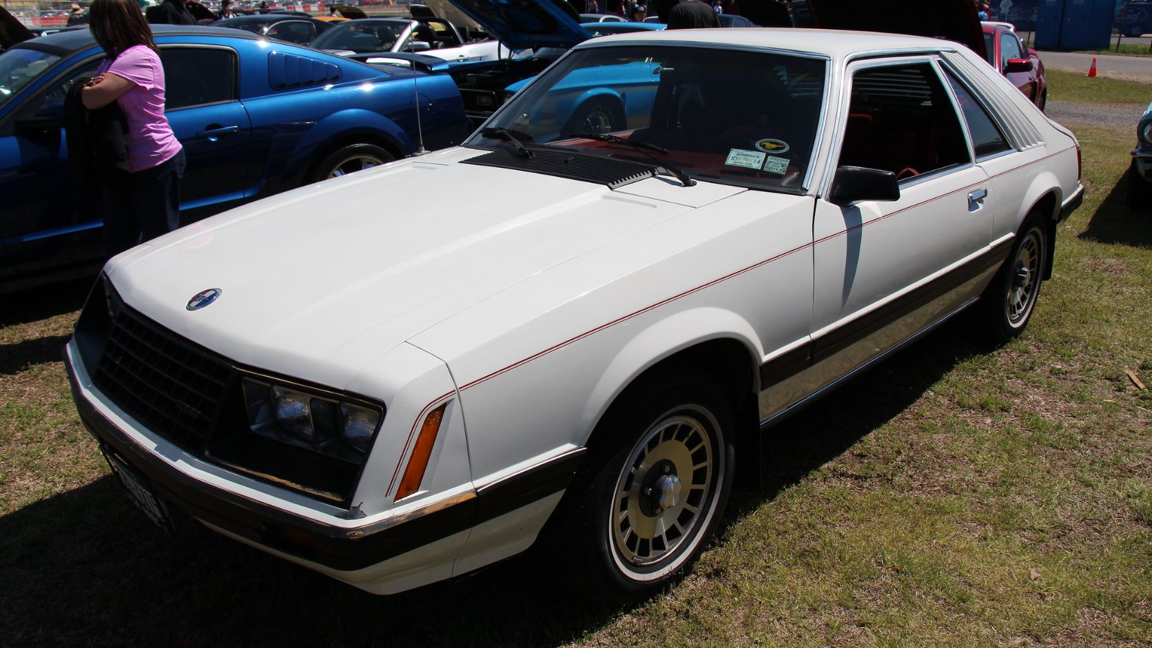 White 1980 Ford Mustang Ghia hatchback with red pinstripes, front three-quarter view